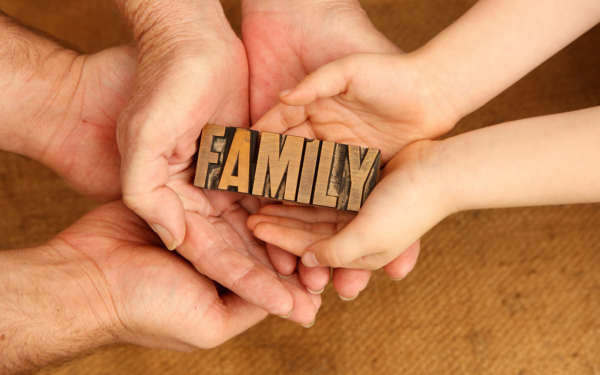 Hands holding a wooden block that says FAMILY